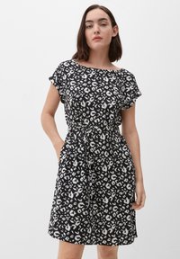Sukienka w czarno-białą panterkę z krótkimi rękawami, okrągłym dekoltem, przeszywaną talią, bocznymi kieszeniami i zwiewnym dołem. Gładka faktura tkaniny.