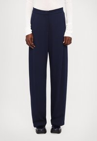 Wide-leg navy trousers with a smooth texture and elastic waistband, featuring front pockets and tailored seams for a structured look.