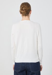 Biały sweter z długim rękawem, wykonany z miękkiego materiału, z okrągłym dekoltem i ściągaczem u dołu. Tył ma gładką, nieozdobioną teksturę.