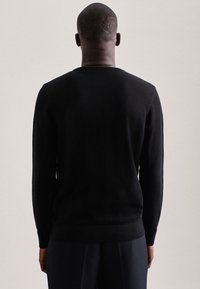 Maglione nero lavorato a maglia con colletto rotondo, maniche lunghe e vita aderente. Il tessuto ha una finitura strutturata, visto da dietro.