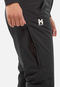 Schwarze Hose mit einer Reißverschlusstasche an der Seite, ausgestattet mit einem Netzfutter. Ein weißes Logo "MILLET" ist auf der Vorderseite sichtbar.