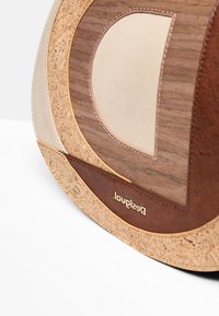 Borsa rotonda con pannelli beige, marroni, in sughero e effetto legno, dotata di un piccolo logo dorato del brand sulla sezione in pelle marrone.