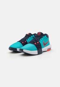 Turquoise en marineblauwe sportschoenen met ademend mesh, een gevoerde kraag en rode accenten, met een witte zool en zichtbare luchtkussens.
