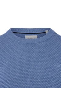 Niebieski sweter dzianinowy z teksturowanym wzorem, okrągłym dekoltem i ściągaczami. Posiada małe logo marki z przodu.