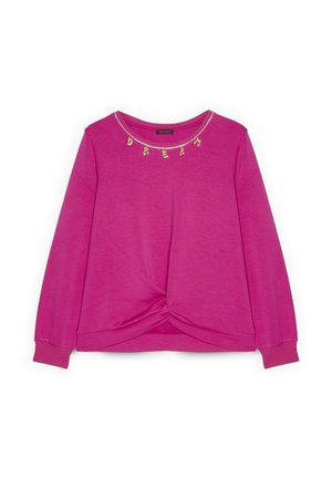 Kirkkaan pinkki pitkähihainen paita, jossa on solmittu solmudetalji helmassa ja kaulanauhassa kullanvärisiä kirjainriipuksia, jotka muodostavat sanan "Dream".