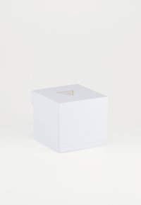 Cutie decorativă albă cu un finisaj texturat, având un logo triangular auriu în partea de sus. Cutia are un design simplu și minimalist.