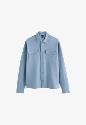 Chemise boutonnée bleu clair en tissu doux. Dispose de deux poches frontales avec rabats, d'un col pointu et d'une coupe décontractée avec des manches longues.