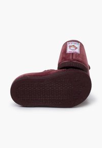 Pantofole bordeaux con una morbida texture in velluto, punta tonda, caviglia a coste e suola in gomma. Presentano un'etichetta colorata con un design di scimmia.
