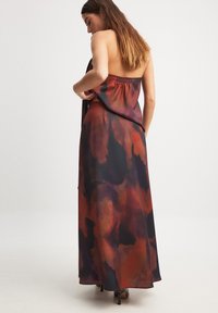 Maxi dress in lightweight fabric featuring a multicolored abstract pattern in deep reds and blacks, with a smocked back detail.