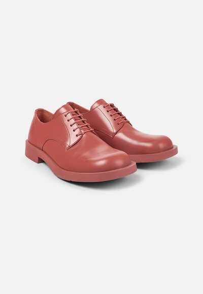 Red leather lace-up shoes with a smooth finish, rounded toe, and a flat rubber sole. Features subtle stitching and a low-profile design.