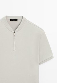 Lysegrå polo i kortærmet design med en lille opretstående krave og en kort lynlås foran, ensfarvet.