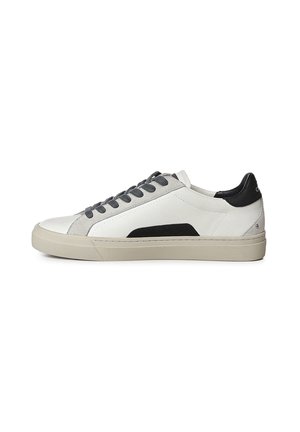 Zapatilla baja blanca con parche negro en el talón, cordones grises, suela beige claro y detalle lateral negro, mostrada desde el lado exterior.