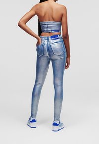 Siniset venytettävät skinny-farkut, joissa on korkea vyötärö, hillitty haalistuminen ja kaksi takataskua. Yhdistetty vastaavaan lyhytvartiseen toppiin, joissa molemmissa on etiketti.