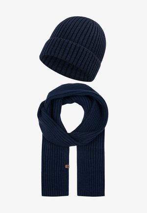 Strickmütze und Schal-Set in dunklem Marineblau mit gerippter Textur. Der Schal ist lang und flach und hat ein kleines Logo-Tag.