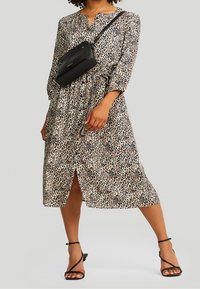 Robe midi à imprimé léopard avec manches longues, col en V, taille cintrée, fente, assortie d'un sac bandoulière noir et de talons à brides.