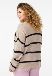 Bež pleten pulover s črnimi vodoravnimi črtami, ohlapnega kroja, okroglega izreza in rebrastimi manšetami, ki prikazuje teksturo in oblikovne podrobnosti.
