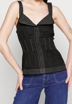 Černý tílko bez rukávů s bílými prošitými liniemi na límci a přední straně, doplněný modrými džínami.