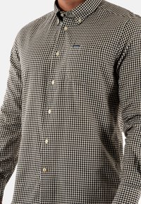 Gekelfde button-down shirt in zwart-wit, met een puntige kraag, lange mouwen en een klein borstzakje. Gemaakt van katoen.
