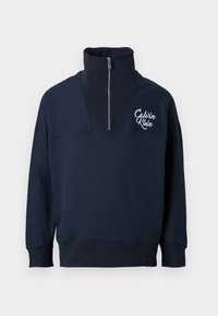 Navy blue cotton pullover with a high collar, half-zip closure, and white Calvin Klein logo on the chest. Features ribbed cuffs and hem.
