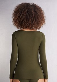Olivengrünes Langarmoberteil in einem glatten, körperbetonten Design. Mit rundem Ausschnitt und nahtlosen Schulternähten. Minimalistischer Stil.