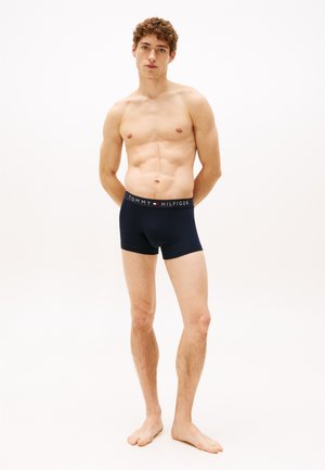 Marineblaue Boxer-Shorts mit einem Markenbund, der "TOMMY HILFIGER" trägt. Weiches Baumwollmaterial mit eng anliegendem Schnitt und glatter Textur.