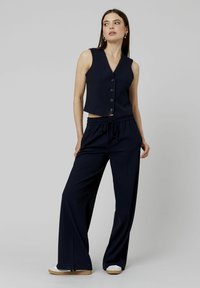 Ensemble deux pièces à rayures marines comprenant un gilet sans manches avec fermeture à boutons et un pantalon large avec une ceinture élastique.
