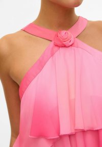 Roze chiffon haljina s halter izrezom i ružom kao detaljem. Lagana i prozračna tkanina s višeslojnim volanima i glatkom teksturom.