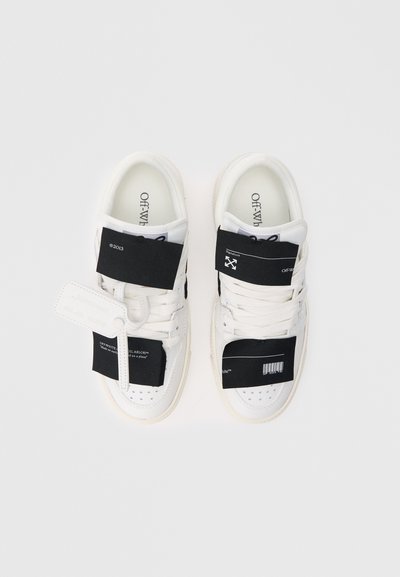 Adidași albi cu superior din piele texturată, având bretele Velcro negre, șireturi în contrast și branding brodat pe branț și etichete.