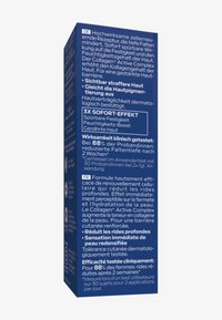 Blauer rechteckiger Kasten mit Texten auf Deutsch und Französisch, der Hautpflegevorteile beschreibt; Verpackung enthält Produktansprüche und Anwendungshinweise.