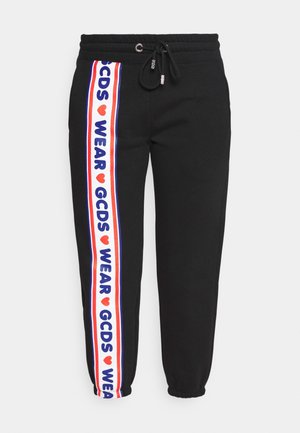 Musta juoksuhousut, joissa on joustava vyötärönauha ja kiristysnauha, vasemmassa lahkeessa pystysuora valkoinen raita, jossa punaisia sydämiä ja sininen teksti "GCDS WEAR".