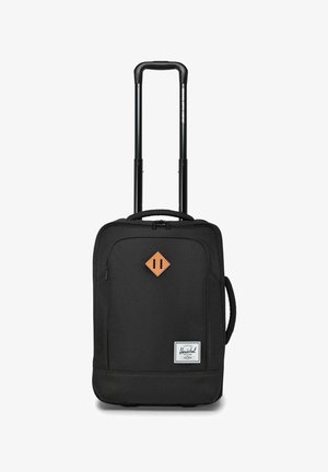 Valise à roulettes noire en tissu souple avec une poignée extensible, poche zippée à l'avant, poignée latérale et patch en forme de diamant marron à l'avant.