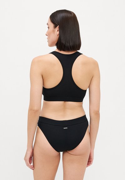 Black ribbed sports bra with a racerback design paired with matching high-waisted briefs, featuring a subtle logo on the waistband.