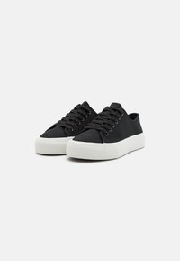 Schwarze Leinensneaker mit weißen Gummisohlen, ausgestattet mit einem Schnürdesign und einer runden Zehenpartie, ideal für die Freizeit.