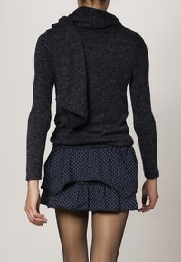 Námořnický pletený svetr s rolákem, kombinovaný s vícevrstvou námořnickou sukní s bílými puntíky. Měkká textura a přiléhavý střih.