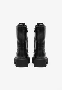 Bottines en cuir noir avec une finition lisse, des semelles épaisses et des fermetures éclair latérales. Présentent un design légèrement effilé en haut.