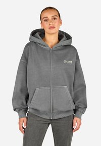 Γκρι φούτερ με φερμουάρ, κατασκευασμένο από μαλακό υλικό, διαθέτει κουκούλα, μπροστινές τσέπες και το κείμενο "PEGADOR" σε αντίθετο χρώμα στο στήθος.