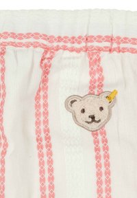 Tissu blanc avec des rayures décoratives roses, présentant un motif en broderie de ours texturé. L'ours a un accent de corne jaune.