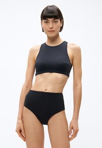 Čierny bikiny set s vrchným dielom s vysokým golierom a spodným dielom s vysokým pásom, vyrobený z hladkej, elastickej látky s jednoduchými líniami bez viditeľných vzorov.