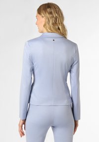 Helleblaue maßgeschneiderte Blazer aus glattem Stoff. Mit einem spitzen Kragen und einem kleinen Knopfakzent auf der Rückseite. Figurbetontes Design.