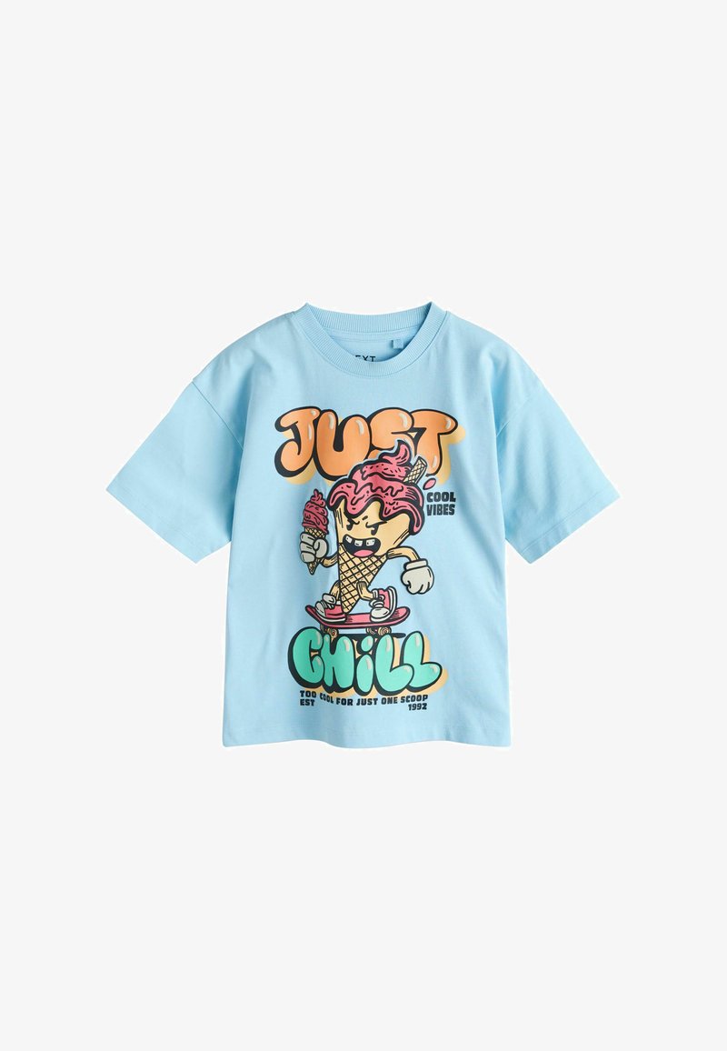 T-shirt bleu clair avec un personnage de cornet de glace en dessin animé sur un skateboard tenant une glace, légendé "Just Chill" et "Cool Vibes."