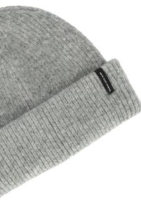Grijze gebreide beanie met een geribbelde structuur, voorzien van een omgeslagen boord en een klein zwart label aan de zijkant.