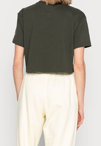 Lyhythihainen, tummanvihreä puuvillapaita, jossa on pyöreä pääntie ja yksinkertainen helma. Paidassa ei ole näkyviä logoja tai kuvioita.