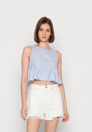 Top crop em xadrez azul claro com bainha com babados, emparelhado com calções brancos desgastados com bordas desfiadas e bolsos frontais.