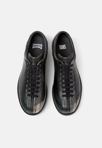 Sneaker in pelle nera con punte arrotondate, dotate di lacci neri e etichette del marchio "CAMPER" e "TWINS" visibili sulle solette.