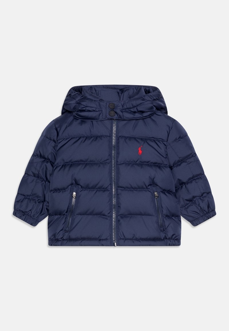 Tmavě modrá péřová bunda s kapucí, krátkými rukávy, zapínáním na zip a dvěma kapsami na bocích. Dokončena malým červeným logem.