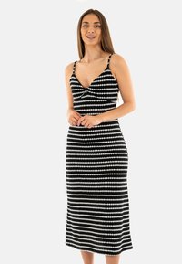 Abito midi a motivi in bianco e nero con scollo basso, spalline sottili e silhouette aderente con un leggero svaso all'orlo.