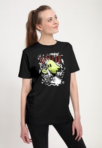 Černé bavlněné tričko se žlutým designem karikatury ducha, s červenými akcenty a textem ve stylu graffiti v bílé a černé barvě. Volný střih.