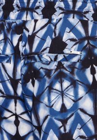 Blue and white patterned fabric with a geometric design, featuring two back pockets and a small metallic logo accent. Smooth texture.