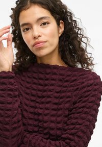 Bordeaux tekstureret sweater med et hævet mønster; har en rund halsudskæring og sammensugne ærmer, fremstillet af blødt, strækbart materiale.
