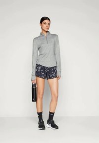 Grå langermet genser med kvart glidelås, svart og grå mønstrede shorts, svart drikkeflaske, svarte joggesko, svarte sokker, minimalistisk design.